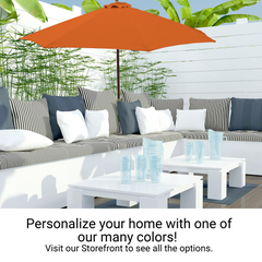 A stylish outdoor patio features a white sectional sofa with black and white striped, and solid-colored cushions. Providing shade overhead is the Formosa Covers 9ft Market Patio Umbrella 8 Rib Replacement Canopy in Tuscan Orange. In the foreground, white coffee tables are adorned with clear glassware, while greenery frames the scene.