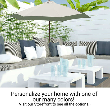 A cozy outdoor patio setup featuring a white L-shaped sectional sofa with striped and solid pillows, a large gray umbrella outfitted with the Formosa Covers 9ft Market Patio Umbrella 6 Rib Replacement Canopy in Duet Sage Green, a white coffee table with clear plastic cups, and lush green plants in the background. Text reads: "Personalize your home with one of our many colors! Visit our Storefront to see all the options.