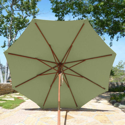 The 9ft Market Patio Umbrella from Formosa Covers, featuring a Seafoam Green Replacement Canopy and supported by eight wooden ribs and a pole, is opened to display its underside. It is set up on a stone patio surrounded by trees and shrubs under a clear sky. The durable polyester fabric ensures long-lasting use in outdoor settings.