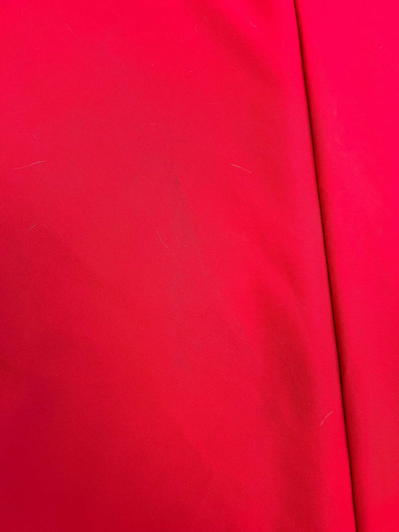 A close-up image of the Formosa Covers Cosmetic Defect- Open Box 9ft Market Patio Umbrella 8 Rib Replacement Canopy in red, showcasing its durable 300 denier fabric with a smooth texture. A visible seam runs vertically on the right side of the canopy. The surface appears slightly wrinkled with a few specks and faint lines.