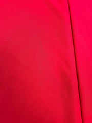 A close-up image of the Formosa Covers Cosmetic Defect- Open Box 9ft Market Patio Umbrella 8 Rib Replacement Canopy in red, showcasing its durable 300 denier fabric with a smooth texture. A visible seam runs vertically on the right side of the canopy. The surface appears slightly wrinkled with a few specks and faint lines.